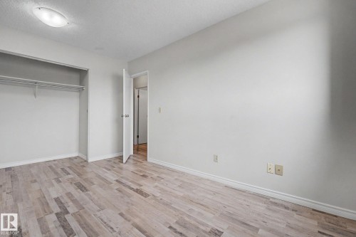 Spacious interior room featuring wood-finish flooring, white baseboards, and a built-in closet with shelving and hanging rod - 1096 Knottwood Road Nw, Edmonton, AB - Indoor Photo Showing Other Room