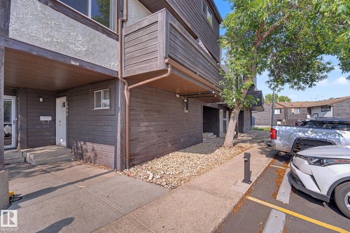 Multi-story exterior with a covered entry, dark horizontal siding, a light stucco upper level, and an upper-level balcony - 1096 Knottwood Road Nw, Edmonton, AB - Outdoor