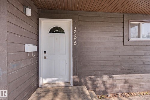 Entryway featuring a white paneled door with an arched transom, horizontal wood siding, a recessed window, and exterior lighting - 1096 Knottwood Road Nw, Edmonton, AB - Outdoor With Exterior