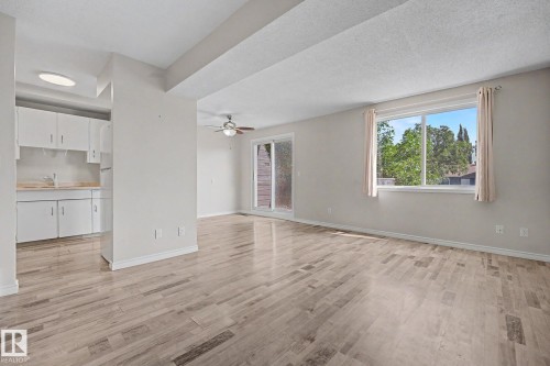 Spacious living area featuring wood-finish flooring, a ceiling fan, and a sliding glass door - 1096 Knottwood Road Nw, Edmonton, AB - Indoor