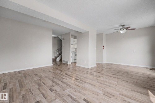 Spacious open-concept living area featuring wood-finish flooring, neutral wall tones, and a ceiling fan with integrated lighting - 1096 Knottwood Road Nw, Edmonton, AB - Indoor Photo Showing Other Room