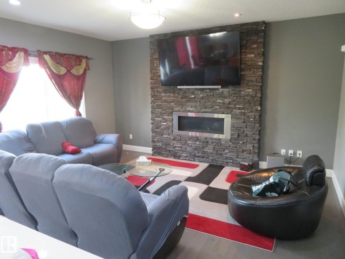 Stacked stone fireplace with a linear insert, recessed lighting, and wood-finish flooring - 3233 Winspear Crescent Sw, Edmonton, AB - Indoor Photo Showing Living Room With Fireplace