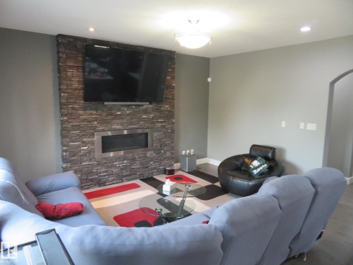 Stone-clad feature wall with built-in linear fireplace and mounted television - 3233 Winspear Crescent Sw, Edmonton, AB - Indoor Photo Showing Living Room With Fireplace