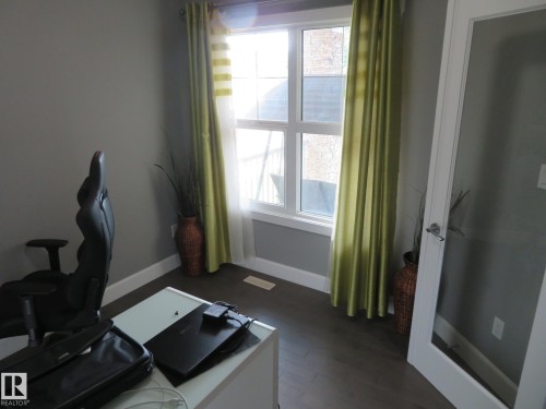 Recessed window with white trim, dark wood-finish flooring, and a frosted glass panel door with chrome hardware - 3233 Winspear Crescent Sw, Edmonton, AB - Indoor