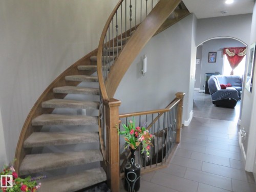 Curved staircase with wood-finish handrail, wrought iron balusters, and carpeted treads - 3233 Winspear Crescent Sw, Edmonton, AB - Indoor Photo Showing Other Room