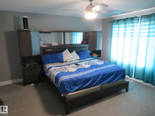 Ceiling fan with integrated lighting, wall-to-wall carpeting, window with curtain rod, built-in headboard unit with storage - 3233 Winspear Crescent Sw, Edmonton, AB - Indoor Photo Showing Bedroom
