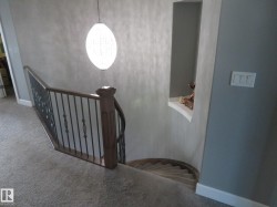 Carpeted curved staircase with wrought iron balusters and a wood-finish handrail - 