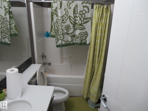 White drop-in bathtub with shower, white toilet, and a white vanity with an integrated sink - 3233 Winspear Crescent Sw, Edmonton, AB - Indoor Photo Showing Bathroom