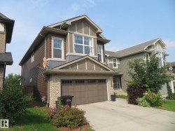 Multi-story residence featuring a gabled roofline, stone facade accents, and a two-car garage - 