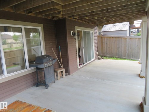 Covered concrete patio with white framed windows and a sliding glass door - 3233 Winspear Crescent Sw, Edmonton, AB - Outdoor With Deck Patio Veranda With Exterior