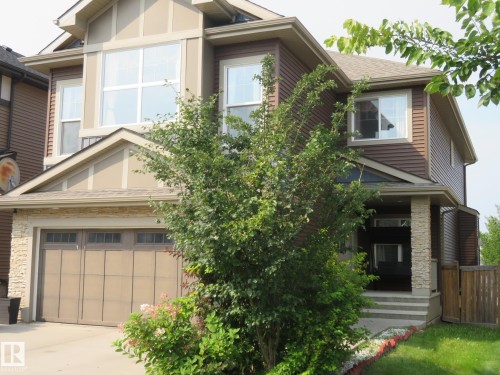 Contemporary exterior featuring brown siding, stone accents, multiple large windows, an attached garage, and a covered front entry - 3233 Winspear Crescent Sw, Edmonton, AB - Outdoor