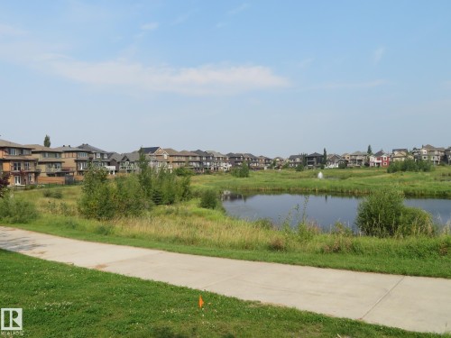 Concrete pathway bordered by green lawn and natural landscape - 3233 Winspear Crescent Sw, Edmonton, AB - Outdoor With View