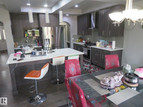 Contemporary kitchen featuring wood-finish cabinetry, stainless steel appliances, a center island with a sink, and pendant lighting - 3233 Winspear Crescent Sw, Edmonton, AB - Indoor Photo Showing Kitchen With Upgraded Kitchen