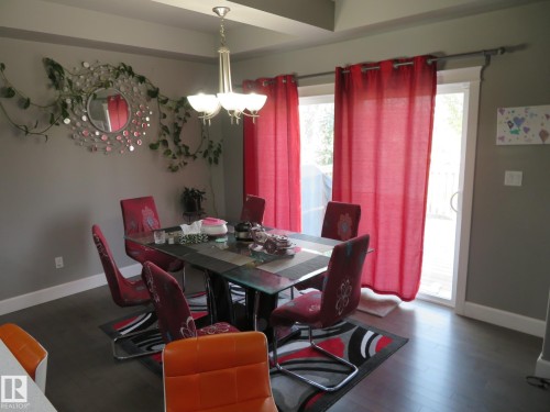 Tray ceiling detail, overhead chandelier, sliding glass door, dark wood-finish flooring, and light gray wall color - 3233 Winspear Crescent Sw, Edmonton, AB - Indoor Photo Showing Dining Room