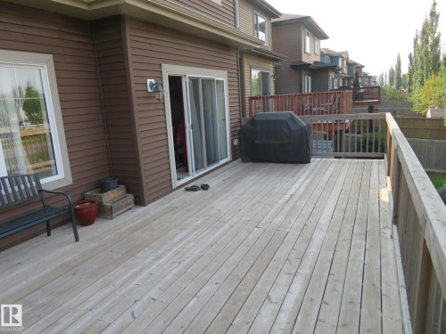 Expansive wood-plank deck with railing, sliding glass door access, and exterior wall sconce - 3233 Winspear Crescent Sw, Edmonton, AB - Outdoor With Deck Patio Veranda With Exterior