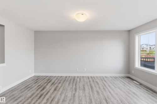 Light gray walls with white trim, wood-finish flooring, and a flush mount ceiling light - 7 Mclean Court, Leduc, AB - Indoor Photo Showing Other Room