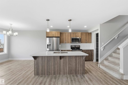 Kitchen featuring wood-finish cabinetry, stainless steel appliances, and a central island with a light-toned countertop - 7 Mclean Court, Leduc, AB - Indoor Photo Showing Kitchen With Stainless Steel Kitchen With Upgraded Kitchen