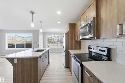Kitchen featuring wood-finish cabinetry, stainless steel appliances, white subway tile backsplash, and a center island with a sink and pendant lighting - 7 Mclean Court, Leduc, AB - Indoor Photo Showing Kitchen With Upgraded Kitchen