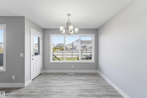 Wood-finish flooring, white trim, natural light, and a modern chandelier - 7 Mclean Court, Leduc, AB - Indoor Photo Showing Other Room
