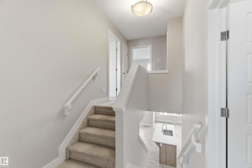 Carpeted staircase with white handrails and painted walls - 7 Mclean Court, Leduc, AB - Indoor Photo Showing Other Room