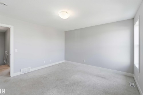 Neutral wall paint, plush carpeting, ceiling-mounted lighting fixture, and a single window - 7 Mclean Court, Leduc, AB - Indoor Photo Showing Other Room