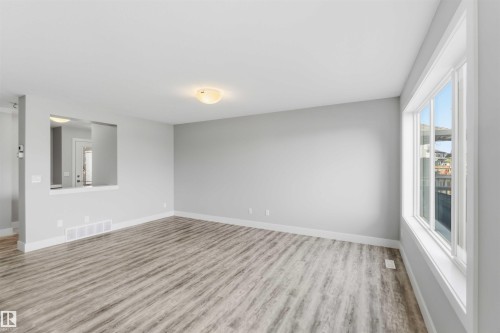 Wood-finish flooring, neutral wall tones, large window, and recessed wall opening - 7 Mclean Court, Leduc, AB - Indoor Photo Showing Other Room