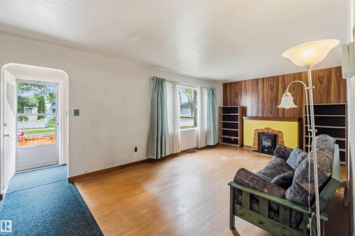 Hardwood flooring, wood-finish accent wall, built-in shelving, and a decorative fireplace - 11710 94 Street Nw, Edmonton, AB - Indoor With Fireplace