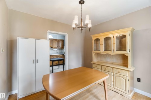 Hardwood-finish flooring, neutral wall paint, and a classic chandelier - 11710 94 Street Nw, Edmonton, AB - Indoor Photo Showing Dining Room