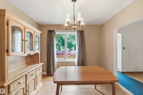Wood-finish flooring with a built-in hutch featuring glass-front cabinetry - 11710 94 Street Nw, Edmonton, AB - Indoor Photo Showing Dining Room