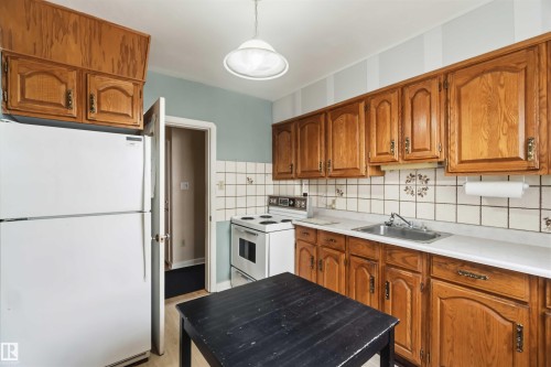 Kitchen featuring wood cabinetry, white countertops, square tile backsplash, and a white ceiling light fixture - 11710 94 Street Nw, Edmonton, AB - Indoor Photo Showing Kitchen