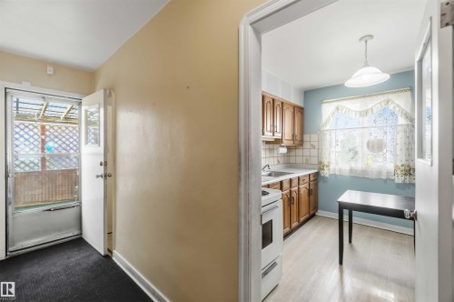 Kitchen featuring wood-finish cabinetry, light-toned countertops, and a full-size range - 11710 94 Street Nw, Edmonton, AB - Indoor Photo Showing Other Room