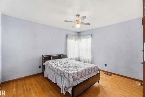 Hardwood flooring, corner window with sheer coverings, and a ceiling fan with integrated lighting - 11710 94 Street Nw, Edmonton, AB - Indoor Photo Showing Bedroom