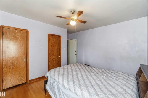 Hardwood flooring, wood doors, ceiling fan with integrated lighting, and painted walls - 11710 94 Street Nw, Edmonton, AB - Indoor Photo Showing Bedroom