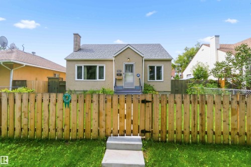 Stucco exterior, gabled roofline, front entry steps, front door with sidelight, and a wood privacy fence - 11710 94 Street Nw, Edmonton, AB - Outdoor