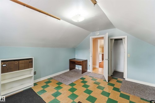Sloped ceiling room featuring a checkered floor, built-in shelving, and a wall-mounted light fixture - 11710 94 Street Nw, Edmonton, AB - Indoor
