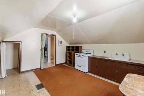 Angled ceiling, built-in cabinetry, gas range, double basin utility sink, and wood-finish flooring - 11710 94 Street Nw, Edmonton, AB - Indoor