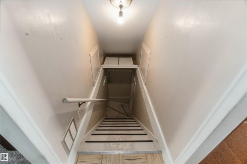 Staircase with light-toned walls, a white handrail, and striped stair treads - 11710 94 Street Nw, Edmonton, AB - Indoor Photo Showing Other Room