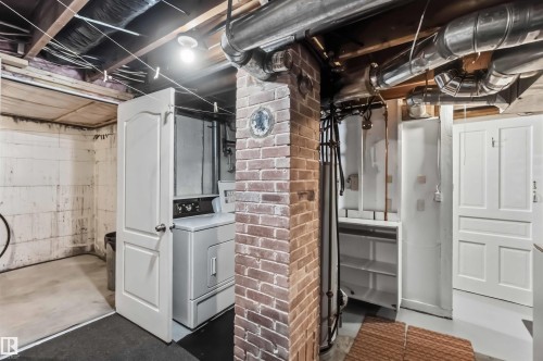 Utility basement featuring exposed brick chimney structure, high ceilings with visible ductwork and mechanical systems, white finished storage cabinetry, concrete flooring, and recessed lighting throughout - 11710 94 Street Nw, Edmonton, AB - Indoor Photo Showing Laundry Room
