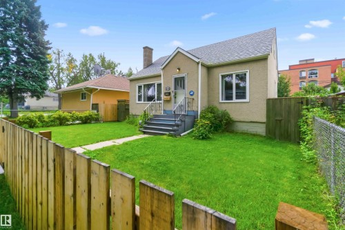 Stucco exterior, front entry porch, multiple windows, asphalt shingle roof, and a wood picket fence - 11710 94 Street Nw, Edmonton, AB - Outdoor