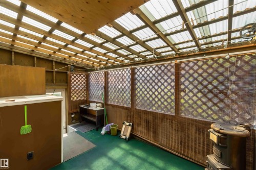 Translucent roof panels, wood lattice wall accents, wood paneling, and a floor-mounted stove - 11710 94 Street Nw, Edmonton, AB - Indoor Photo Showing Other Room