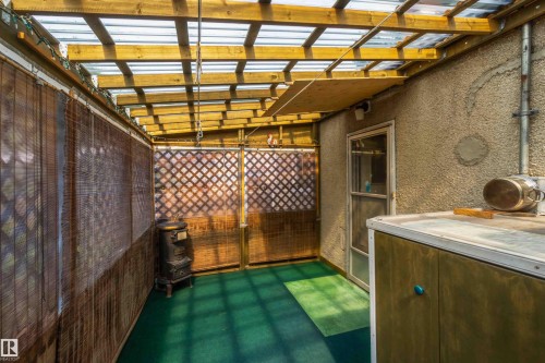 Enclosed outdoor structure with a wood beam and corrugated panel ceiling, textured stucco wall, and a built-in cabinetry unit - 11710 94 Street Nw, Edmonton, AB - Indoor Photo Showing Other Room