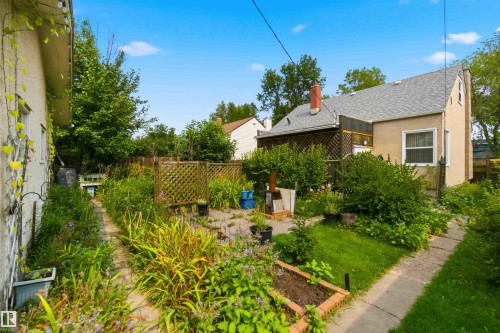 Backyard area featuring a lawn, paved pathways, and an established garden bed - 11710 94 Street Nw, Edmonton, AB - Outdoor