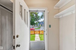 Entryway with a solid white door featuring three upper panels, a screen door, and two white floating shelves - 