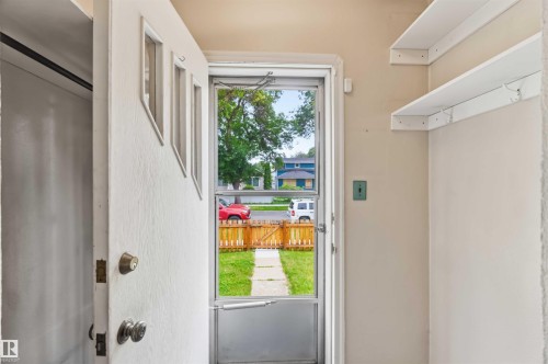 Entryway with a solid white door featuring three upper panels, a screen door, and two white floating shelves - 11710 94 Street Nw, Edmonton, AB - Indoor Photo Showing Other Room