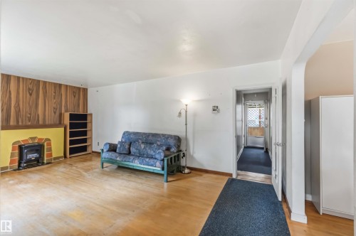 Spacious living area featuring warm wood-finish flooring, recessed ceiling lighting, and abundant natural light - 11710 94 Street Nw, Edmonton, AB - Indoor With Fireplace