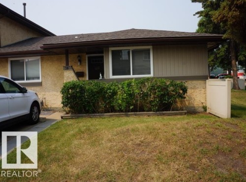 Exterior with stucco and vertical panel siding, featuring a covered entry and dual-pane windows - #38 8930 99 Av, Fort Saskatchewan, AB - Outdoor