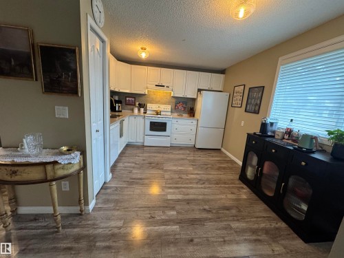 Kitchen featuring wood-finish flooring, white cabinetry, and white appliances - #38 8930 99 Av, Fort Saskatchewan, AB - Indoor Photo Showing Kitchen