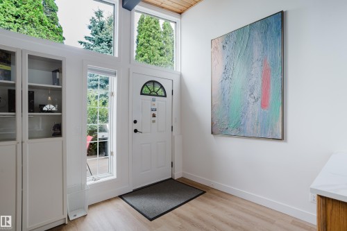 White entryway door with an arched transom window, flanked by tall windows and built-in white cabinetry with glass inserts - 9059 52 Street Nw, Edmonton, AB - Indoor Photo Showing Other Room