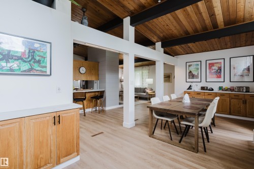 Vaulted wood-paneled ceiling with exposed beams, light wood-finish flooring, built-in wooden cabinetry, and a breakfast bar - 9059 52 Street Nw, Edmonton, AB - Indoor Photo Showing Dining Room