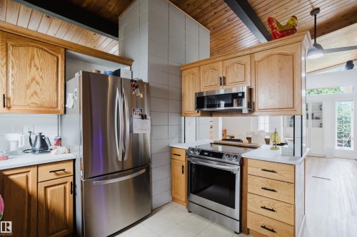 Wood-finish cabinetry, stainless steel appliances, white countertops, wood-paneled ceiling, and light-colored flooring - 9059 52 Street Nw, Edmonton, AB - Indoor Photo Showing Kitchen